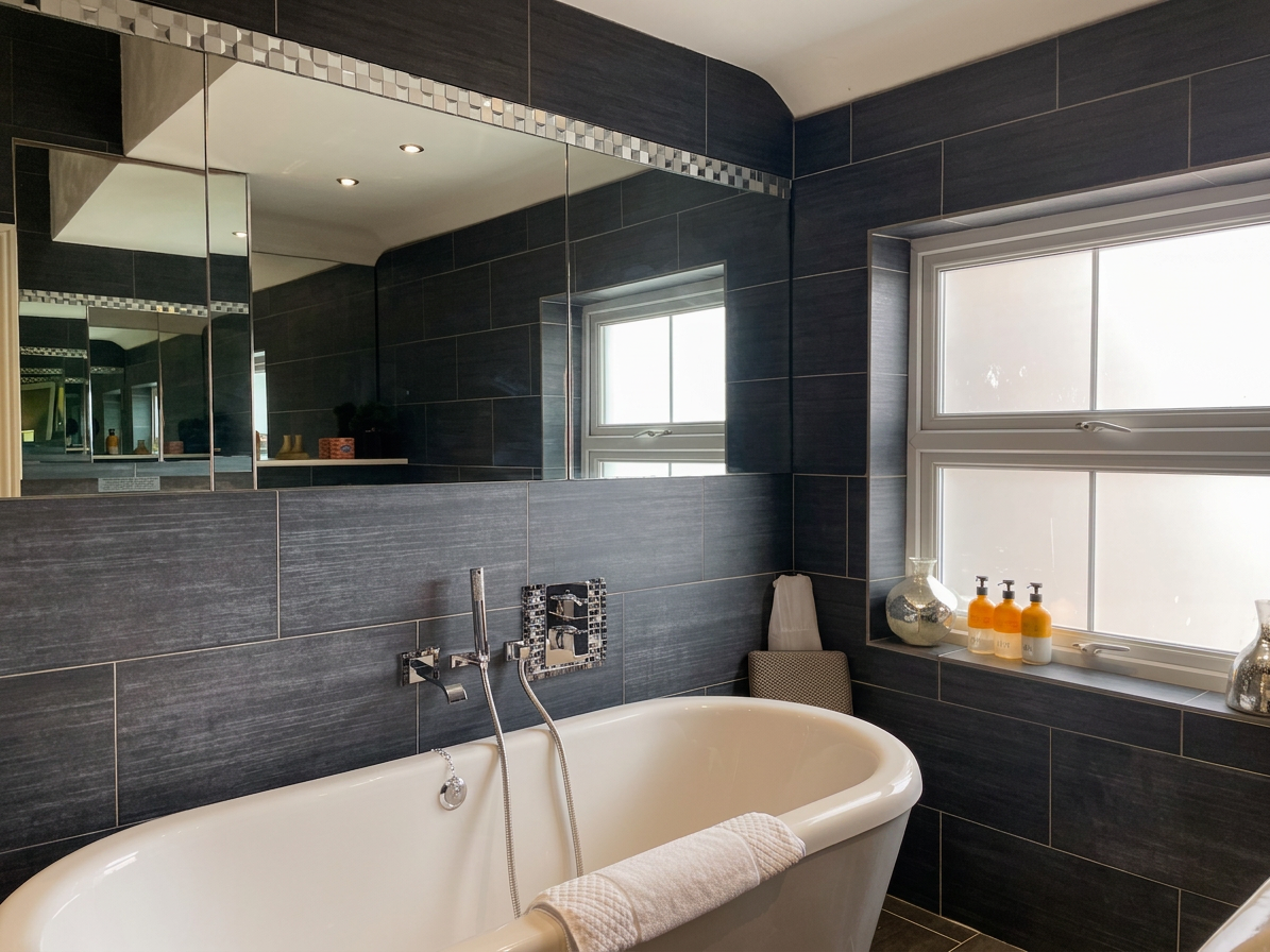Hastings House bathroom with freestanding roll-top bath and charcoal mosaic tiling