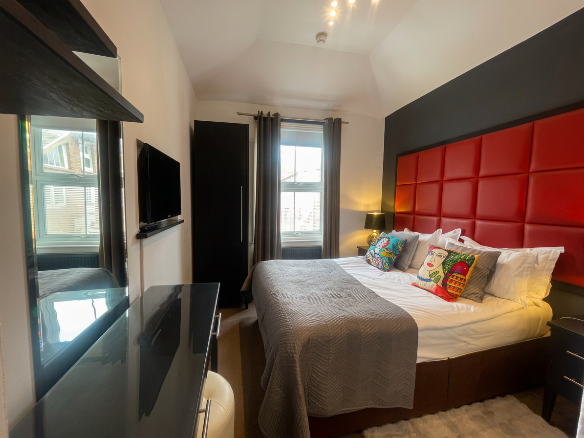 Hastings House bedroom with red tufted headboard and colourful cushions